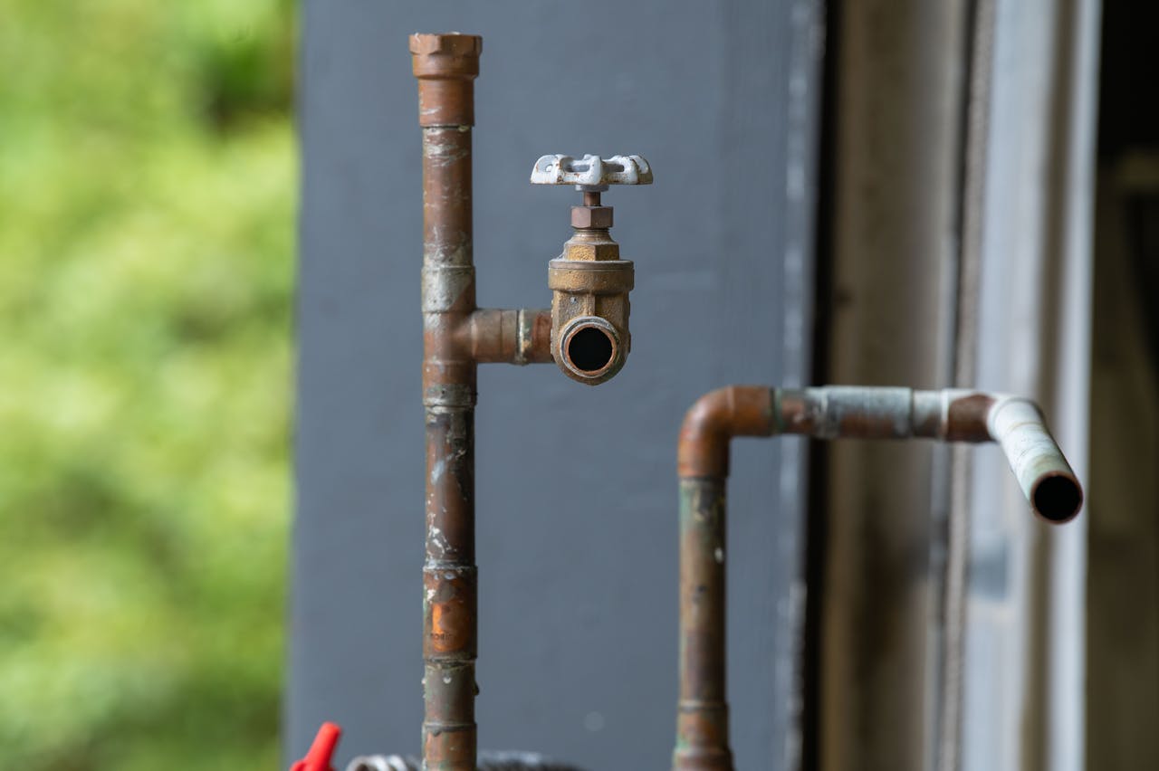 Offerings Detailed view of an old, rusty industrial water pipe with valve, conveying vintage industrial aesthetics.