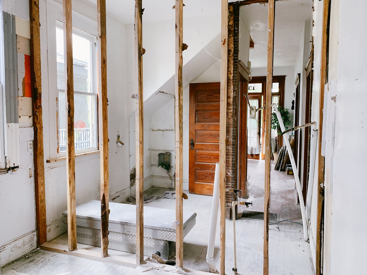 Offerings Interior view of a home under renovation with exposed wooden beams and door.