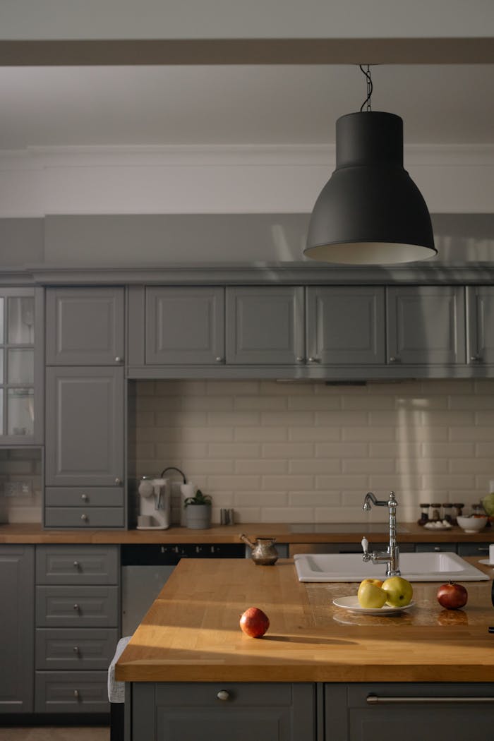 Offerings Stylish modern kitchen interior with gray cabinets and wooden countertops.